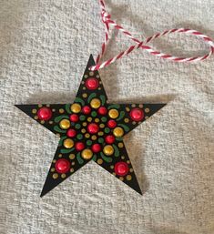 an ornament shaped like a star with red and gold decorations hanging from it's side