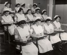 black and white photograph of nurses sitting at desks with books in front of them