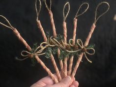 a person holding up some candy canes with green leaves on them and tied to twine