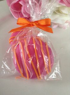 pink and orange striped cookies wrapped in cellophane on a white table with flowers