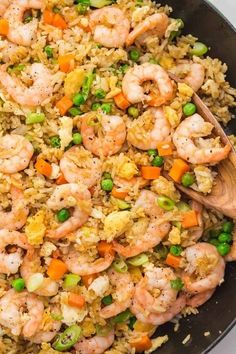 shrimp, peas and rice in a skillet with a wooden spoon on the side