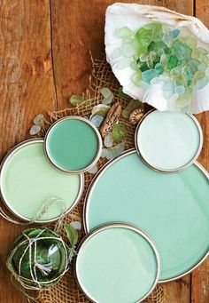 four different shades of paint sitting on top of a wooden table next to a flower