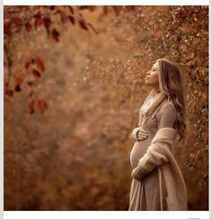 a pregnant woman standing in front of a tree