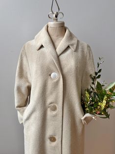 A perfect wardrobe staple from the 1960's.  Loomed in Great Britain, this oatmeal and cream coloured wool beauty features a comfortable overcoat style cut, side hip pockets, oversized button up front and glove length sleeves. A perfect weight for Fall or in between weather.  Beautifully lined in a cream sateen. In excellent vintage condition with no flaws to note.  Has not been professionally dry cleaned yet but presents clean and ready to wear with no marks or stains.  ~ Measurements ~  Size: M Cream Wool Coat With Button Closure, Cream Wool Coat With Button Closure For Fall, Classic Cream Wool Coat With Long Sleeves, Classic Long-sleeved Cream Wool Coat, Classic Cream Pea Coat With Long Sleeves, Vintage Beige Long Sleeve Outerwear, Vintage Beige Outerwear With Lapel Collar, Vintage Beige Single-breasted Outerwear, Retro Beige Long Coat