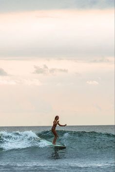 a woman riding a wave on top of a surfboard in the middle of the ocean