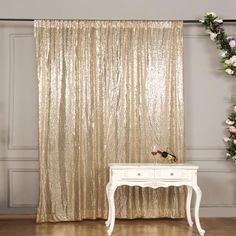 a white table sitting in front of a gold curtain