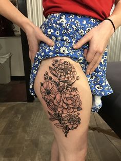 a woman is showing off her thigh with flowers on it