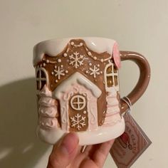 a hand holding a coffee mug with a house on it