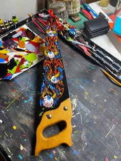 a pair of scissors sitting on top of a table covered in paint and art supplies