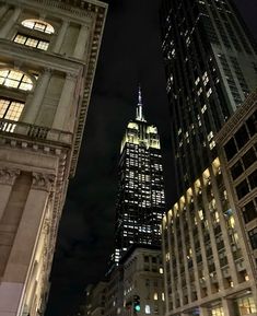 the empire building is lit up at night in new york city, ny on a cloudy day