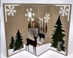 an open card with paper cut out of it and some deer in the woods, on top of snowflakes