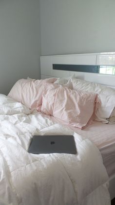 a laptop computer sitting on top of a bed covered in white sheets and pillows,