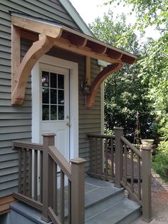 a small house with a white front door and wooden steps leading up to the porch