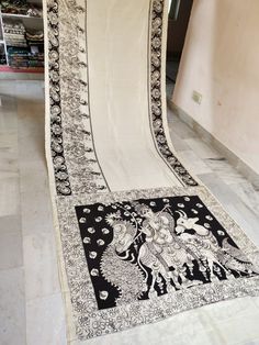 a black and white rug with an intricate design on the bottom is sitting in front of a bookshelf