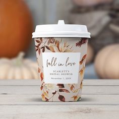 a coffee cup sitting on top of a wooden table next to pumpkins and other decorations