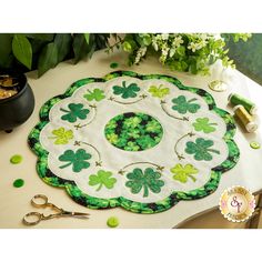 a table topped with green shamrocks next to scissors and potted plants on top of it