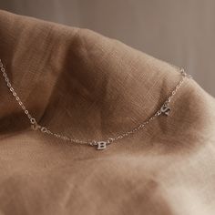 Our delicate Love Notes Necklace is a thing of exquisite beauty and meaning. Its subtly asymmetrical design evokes grace and refinement, while also carrying your most cherished people close to your heart. As we create our jewellery by hand, there will always be variation in alignment and spacing. The beauty of this process is that each KBN piece is unique to its wearer. Delicate Everyday Necklace With Initial Pendant, Dainty Everyday Necklaces With Initials, Delicate Initials Name Necklace For Everyday, Delicate Initial Necklace Gift, Delicate Everyday Name Necklace With Clavicle Chain, Dainty Everyday Name Necklace With Clavicle Chain, Dainty Name Necklace With Clavicle Chain For Everyday, Dainty Sterling Silver Initial Necklace With Clavicle Chain, Dainty Initial Necklace With Delicate Chain For Her