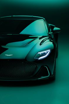 the front end of a black and green sports car with its hood up, on a dark background