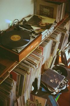 an old record player sitting on top of a wooden shelf filled with records and cds