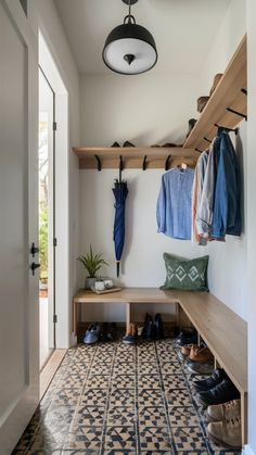 a hallway with tiled flooring and wooden shelves filled with coats, shoes and jackets