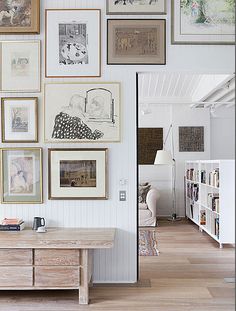 a living room filled with lots of framed pictures on the wall above a wooden coffee table