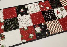 a patchwork christmas table runner with red, white and black squares on it's sides