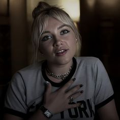 a woman with blonde hair wearing a black and white shirt holding her hand on her chest