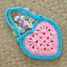 a crocheted bag with buttons in it sitting on a woven tablecloth surface