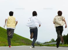 three people are running down the road in their shirts and pants, one is wearing a white shirt