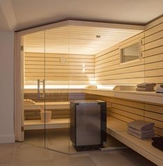 a sauna room with glass walls and wood paneling on the wall, along with towels