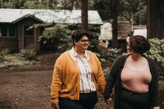 two women walking in the woods holding hands and smiling at each other's company