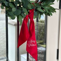 a merry christmas bow hanging from the side of a door with holly and berries on it