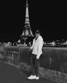 black and white photograph of a man standing in front of the eiffel tower