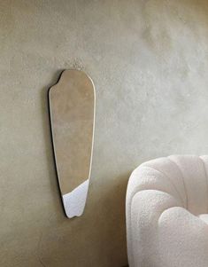 a white chair sitting next to a wall with a mirror on it's side