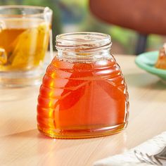 a glass jar filled with honey sitting on top of a table next to two plates