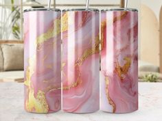 three pink and gold marbled tumbles sitting on a table