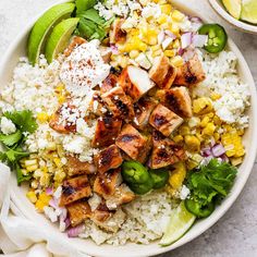 a white bowl filled with chicken and rice next to a lime wedge on the side