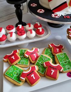 a table topped with cookies and cupcakes covered in frosting next to a cake