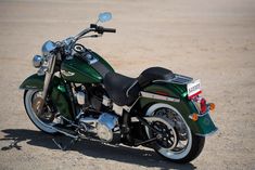 a green and black motorcycle parked in the dirt