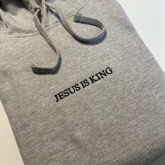 Jesus is King Embroidered T-Shirt, Embroidered Hoodie, Christian Based Clothing, Faith Apparel, Stitched Pullover hooded sweatshirt - Bible Gift Minimalist  - 80% Cotton - 20% Polyester - 7.8 oz/y² Shop: Tiny home shop located in California. All garments are printed to order, handcrafted individually.  I will never use third party cheap labor print shops or mass production drop shippers.  Every Garment is designed, printed, and packaged independently by me. Thank you for supporting someone who i Cotton Long Sleeve Hoodie With Embroidered Text, Cotton Hoodie With Embroidered Text And Long Sleeves, Long Sleeve Cotton Hoodie With Embroidered Text, Streetwear Hoodie With Embroidered Text, Casual Hooded Top With Embroidered Text, Hooded Hoodie With Embroidered Text For Streetwear, Winter Hoodie With Letter Embroidery And Relaxed Fit, Cotton Hooded Sweatshirt With Embroidered Text, Gray Hoodie Sweatshirt With Embroidered Logo