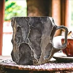 a marbled coffee cup sitting on top of a table next to a tea pot