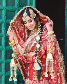 a woman in a red and gold bridal outfit is posing for the camera with her hands on her head