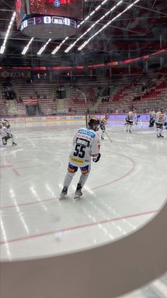 an ice hockey game in progress with the goalie getting ready to kick the puck