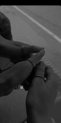 two hands holding each other's wedding rings on their fingers in black and white