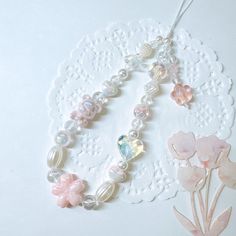 a white doily with pink flowers and pearls on it next to a lace doily