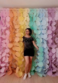 a woman standing in front of a backdrop made of paper flowers