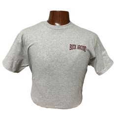 Buck Around and Find Out T-Shirt in Gray Make a bold statement with our "Buck Around and Find Out" T-Shirt in Gray. This t-shirt combines comfort, style, and a touch of humor. Whether you're heading out to the rodeo or just want to showcase your rugged personality, this tee is a must-have addition to your wardrobe. Key Features: Eye-Catching Design: Features the bold and witty phrase "Buck Around and Find Out" printed on the back , making it a conversation starter. Premium Quality Fabric: Made f Heather Grey Graphic Tee With Logo Print, Gray Crew Neck Shirt With Text Print, Heather Grey Crew Neck T-shirt With Graphic Print, Heather Grey Graphic Tee With Text Print, Heather Grey Graphic Tee With Letter Print, Heather Grey Graphic Print Crew Neck T-shirt, Heather Grey Short Sleeve T-shirt With Screen Print, Heather Grey Crew Neck Top With Screen Print, Heather Grey Screen Print Short Sleeve T-shirt