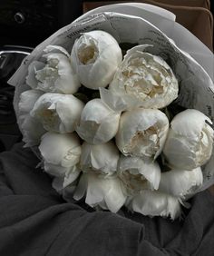 a bouquet of white flowers sitting on top of a black cloth covered car seat cover