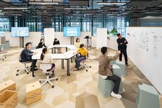 an office with people sitting at desks and writing on the whiteboard in front of them