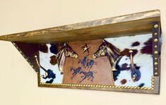 a cow print wall hanging on the side of a wall with gold studded accents